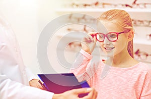 Optician and girl choosing glasses at optics store