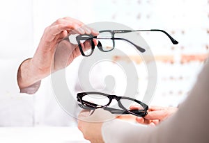 Optician giving new glasses to customer for testing and trying.