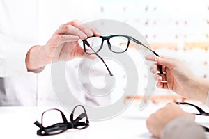 Optician giving new glasses to customer for testing and trying.