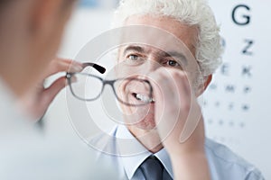 Optician giving new glasses to the patient