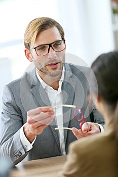 Optician handing new eyeglasses to customer