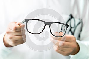 Optician holding glasses. Eye doctor showing new lenses.