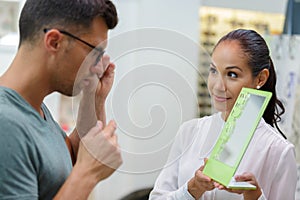 optician holding mirror for customer to appraise eyeglasses photo