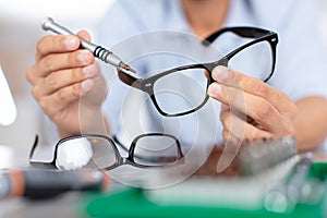 optician measuring and preparing glasses in optical store