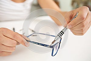 optician repairing broken glasses in workshop
