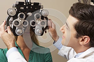 Optician In Surgery Giving Woman Eye Test