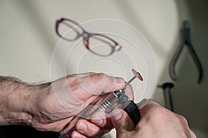 An optician technician polishes the frame of glasses. A professional optician fixes glasses.