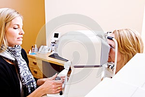 Optician testing eye pressure on client