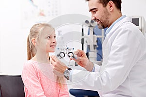 Optician with trial frame and girl at clinic