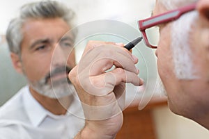 Optician using and ophthalmoscope to look into patients eyes