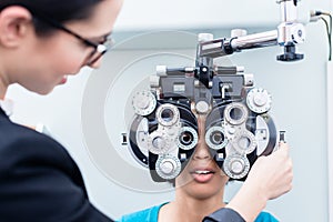 Optician and woman at eye examination with phoropter