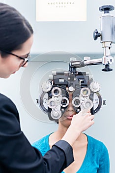 Optician and woman at eye examination with phoropter