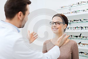 Optician and woman in glasses at optics store