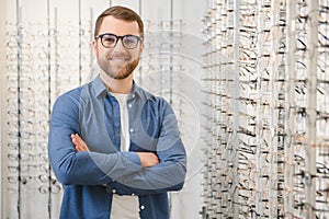 In Optics Shop. Portrait of male client holding and wearing different spectacles, choosing and trying on new glasses at