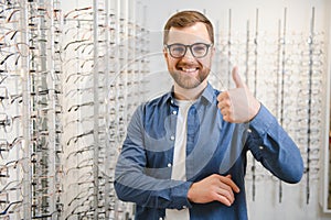 In Optics Shop. Portrait of male client holding and wearing different spectacles, choosing and trying on new glasses at