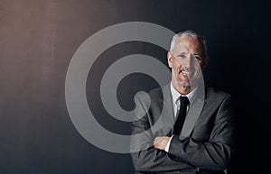 Optimism is a defining characteristic of corporate success. Studio portrait of a mature businessman against a dark