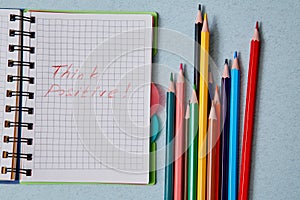 Optimistic Attitude and Happy Concept. Colored pencils and the words think positive in notepad