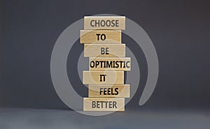 Optimistic is better symbol. Wooden blocks with words Choose to be optimistic it feels better. Beautiful grey background copy