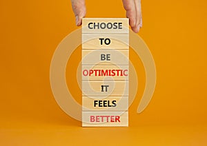Optimistic is better symbol. Wooden blocks with words Choose to be optimistic it feels better. Beautiful orange background copy