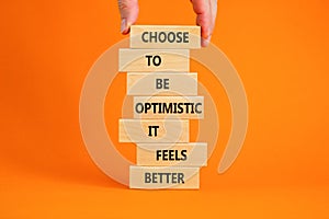 Optimistic is better symbol. Wooden blocks with words Choose to be optimistic it feels better. Beautiful orange background copy