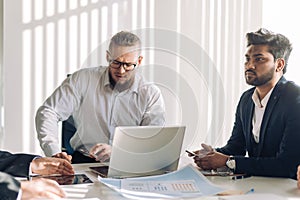 Optimistic businessman in white shirt collaborating with his team at meeting