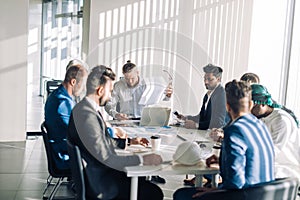 Optimistic businessman in white shirt collaborating with his team at meeting