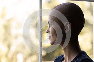 Optimistic cancer woman looking out window with hope