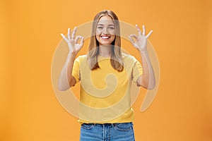 Optimistic charming woman with fair hair and no make-up in yellow t-shirt showing okay or approval gesture assuring