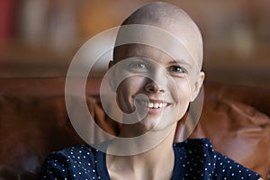 Optimistic female cancer patient sitting on couch looking at camera