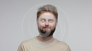 Optimistic funny bearded guy looking at camera cross eyed, showing tongue out, making stupid dumb face