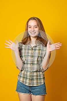 Optimistic girl raises palms from joy, happy to receive awesome present from someone, dressed in casual shirt