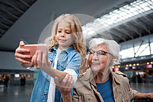 Optimistic granddaughter and her granny are photographing in terminal