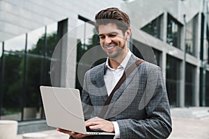 Optimistic handsome business man using laptop