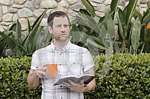 Optimistic man looking out with book and coffee mug in hand.