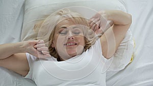 Optimistic middle-aged woman waking up early in the morning, vitality and energy