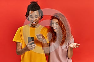 Optimistic young ginger female and Afroman users of smart technology, feel good from successful cellphone updating, gaze