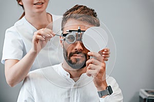 Optometric device. Man`s vision checked by female doctor in the clinic