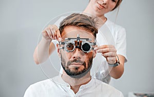 Optometric device. Man`s vision checked by female doctor in the clinic