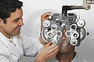 Optometrist Adjusting Panels Of Phoropter While Examining Patient photo