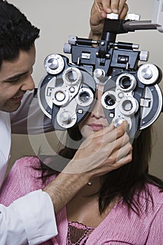 An Optometrist Adjusting Panels Of Phoropter While Examining Patient