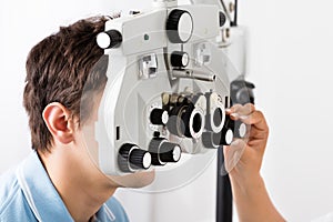 An Optometrist Adjusting Phoropter For Patient