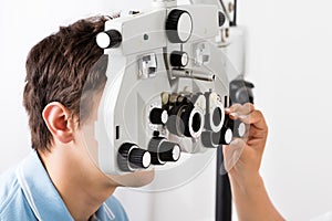 An Optometrist Adjusting Phoropter For Patient photo
