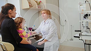 Optometrist checks child`s eyesight - mother and child have consultation in ophthalmologist room