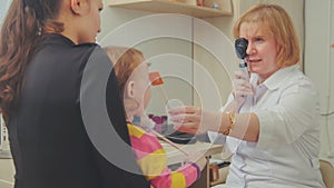 Optometrist checks child`s eyesight - mother and child in ophthalmologist room