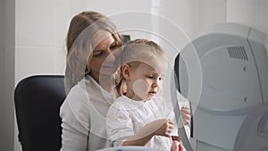 Optometrist checks child`s eyesight - mother and child in ophthalmologist room