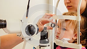 Optometrist checks girl`s eyesight - mother and child have consultation in ophthalmologist room