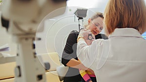 Optometrist checks little girl`s eyesight - mother and child in ophthalmologist room