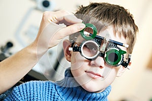 Optometrist doctor examines eyesight of child boy with phoropter