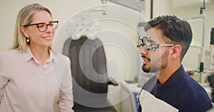 Optometrist doing an eye test on a patient in a clinic. Female optician assessing the vision of a young man with a