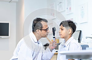 Optometrist doing sight testing for child patient in clinic, Indian child choosing eyeglasses in optics store, Boy doing eye test